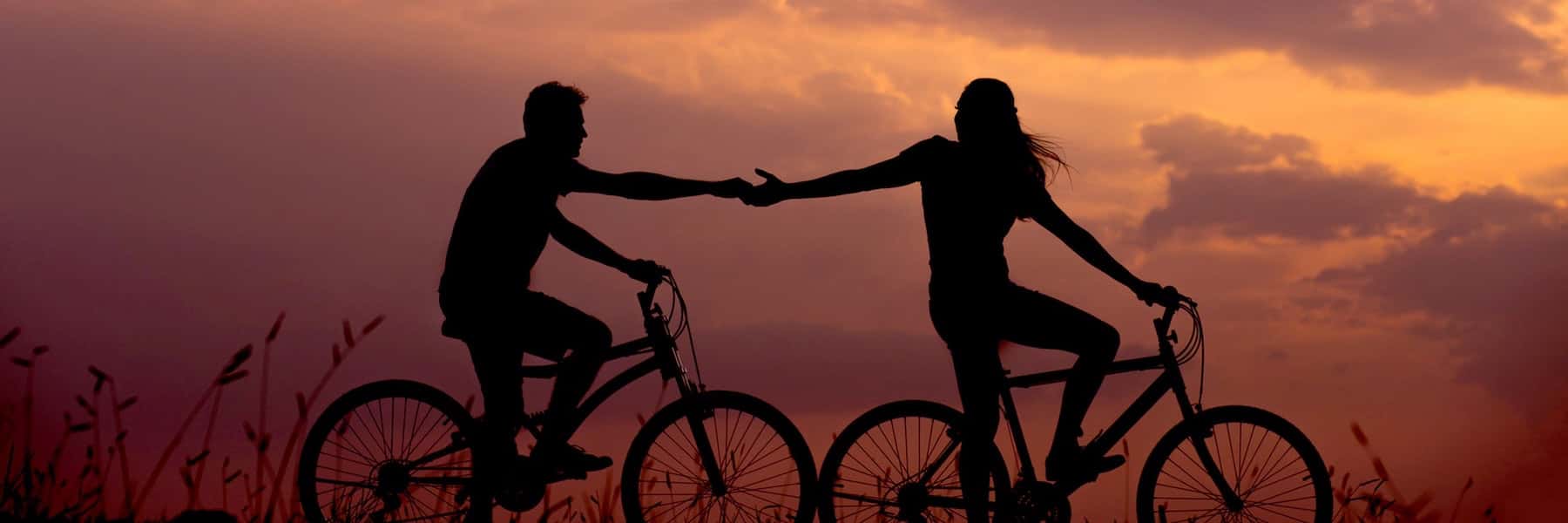 Ett par som cyklar mot en bakgrund av solnedgång